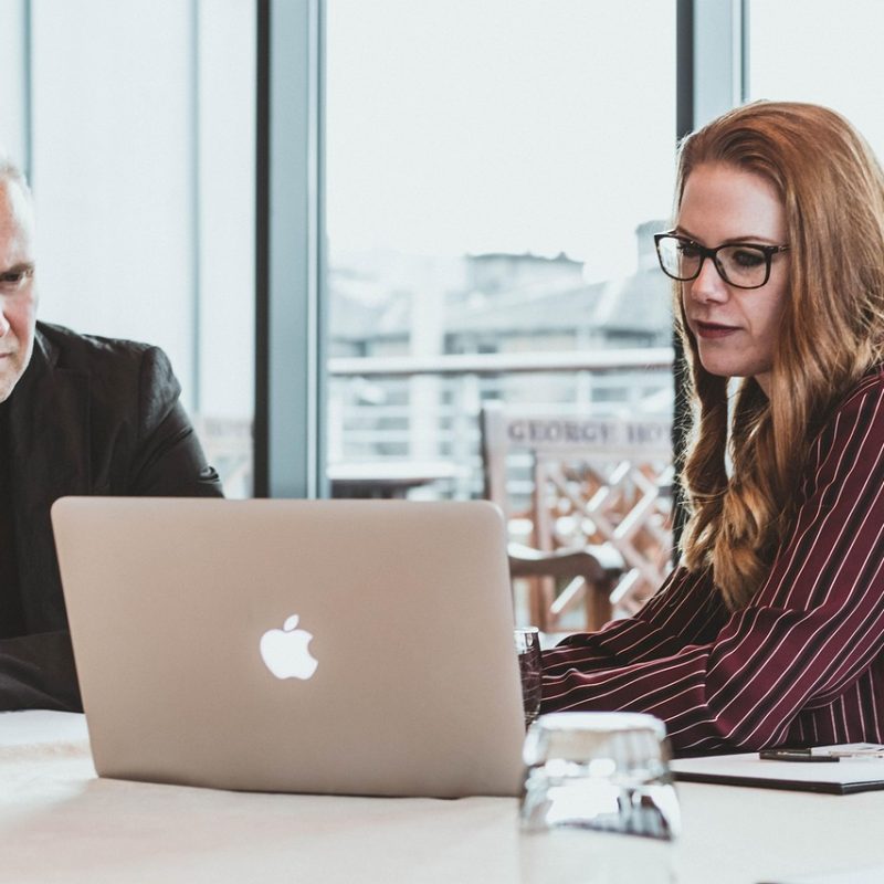 Man and woman sitting together around a laptop, having a meeting - business insurance review